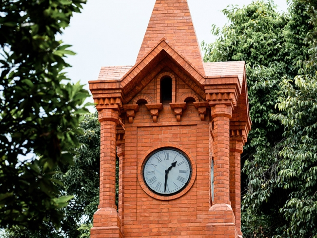 Torre de tijolos à vista com relógio de ponteiros em uma das faces